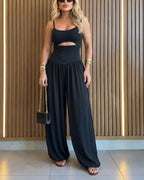 Backless black jumpsuit with cut-out waist and tie-back detail, featuring a stylish lantern silhouette. 0