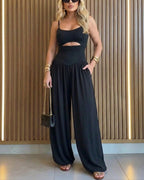 Backless black jumpsuit with cut-out waist and tie-back detail, featuring a stylish lantern silhouette. 2