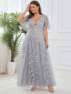 Plus size evening gown with a deep V-neck and a sequinned leaf pattern over tulle.