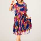 A flowing plus-size summer dress in a vibrant floral pattern with shades of blue and pink, featuring short sleeves. 1