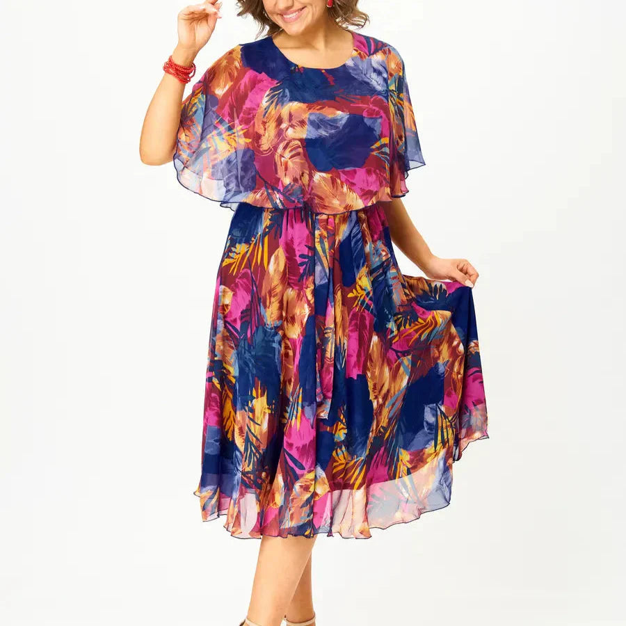 A flowing plus-size summer dress in a vibrant floral pattern with shades of blue and pink, featuring short sleeves. 2