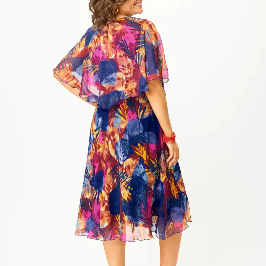 A flowing plus-size summer dress in a vibrant floral pattern with shades of blue and pink, featuring short sleeves. 4