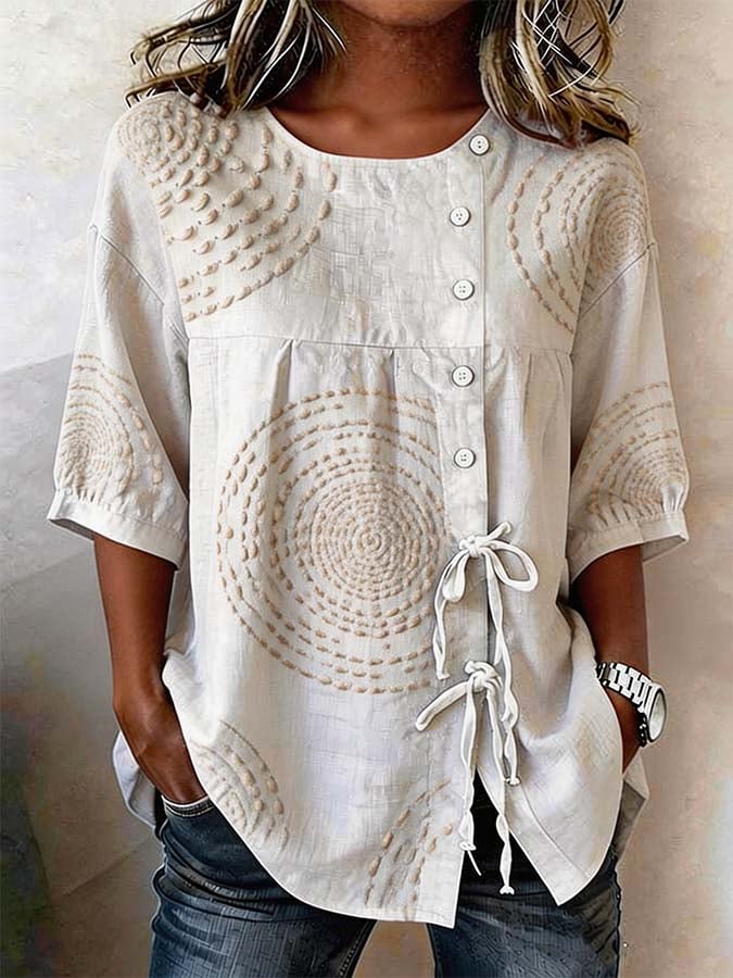 Warm cream casual top featuring raised circular embroidery and a drawstring tie detail. 0