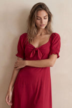 A green fit and flare midi dress with short sleeves and a front tie detail. 2