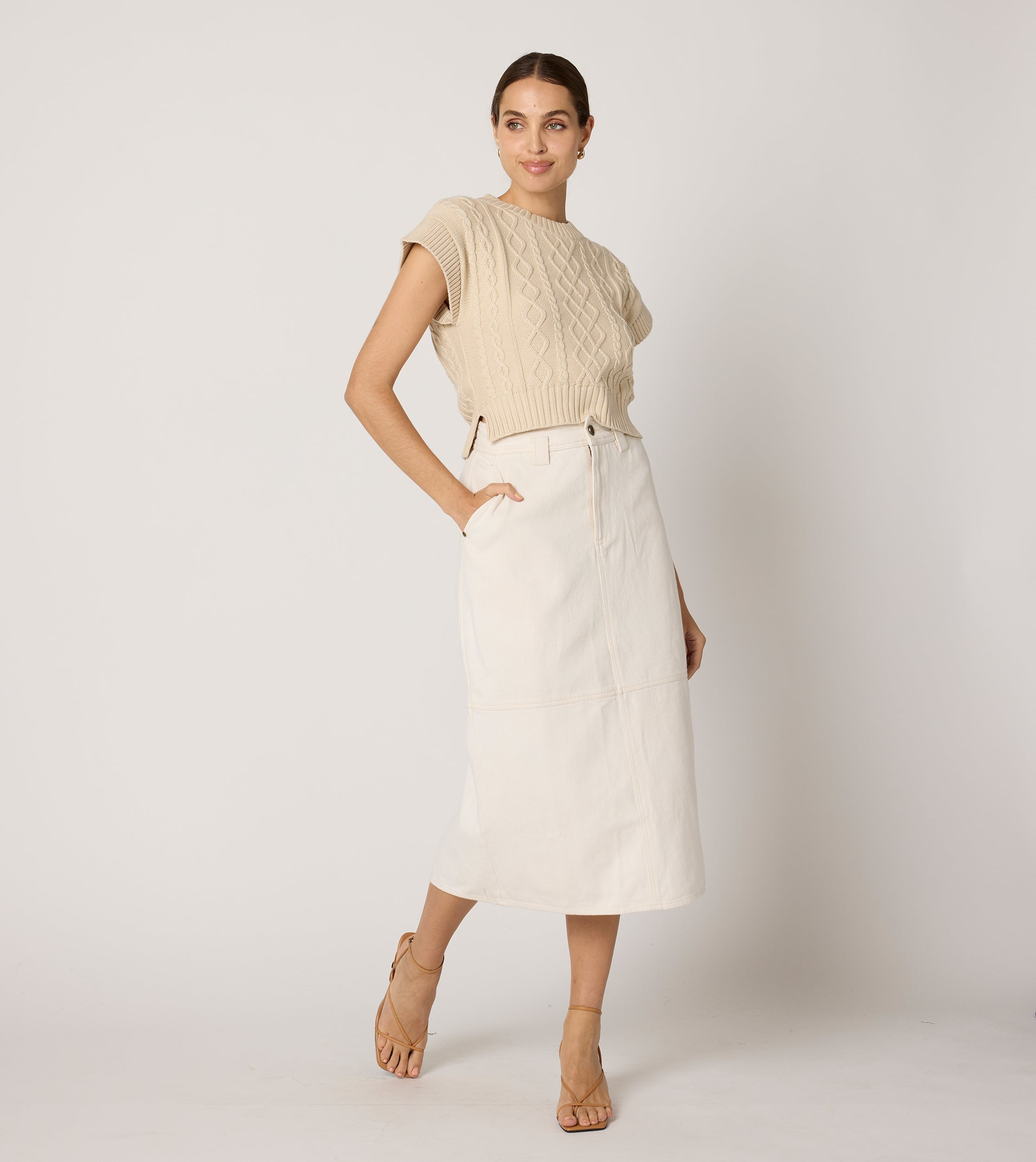 Cream cropped sweater vest in a cozy cable knit style, made from organic cotton for a soft, textured look. 6