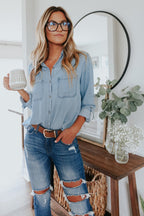Light blue chambray button-down shirt with roll-tab sleeves and pockets, featuring a casual and relaxed style. 0