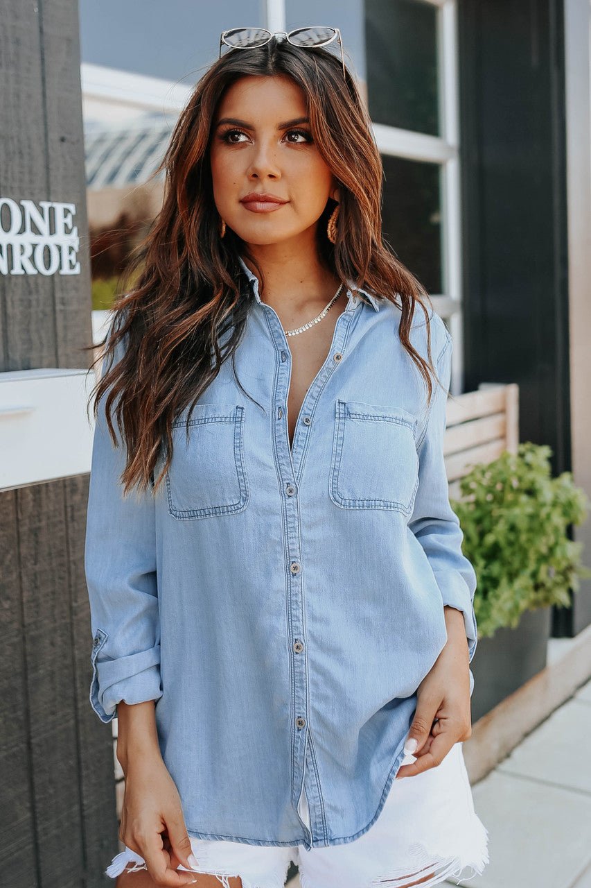 Light blue chambray button-down shirt with roll-tab sleeves and pockets, featuring a casual and relaxed style. 1
