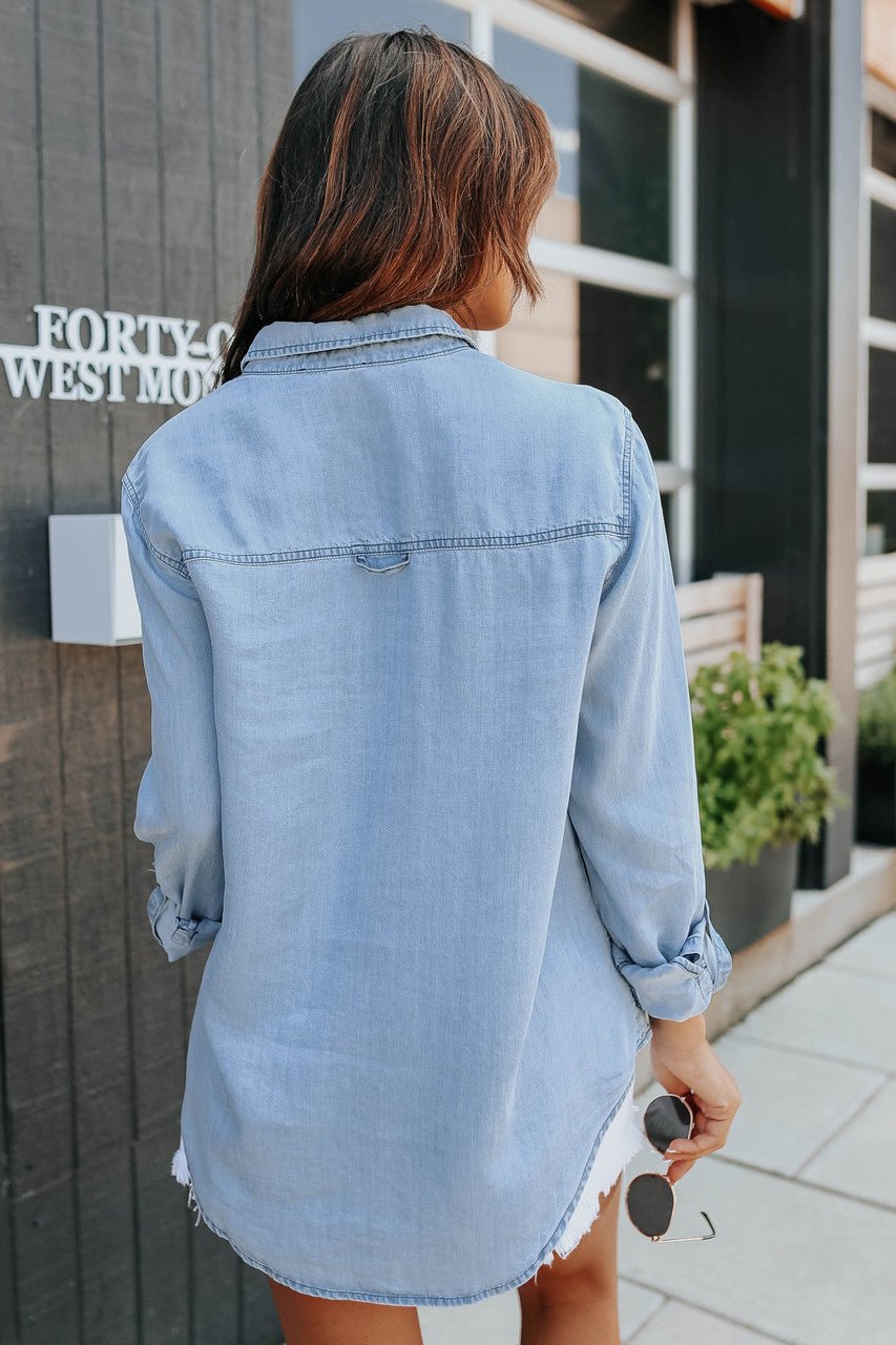 Light blue chambray button-down shirt with roll-tab sleeves and pockets, featuring a casual and relaxed style. 2
