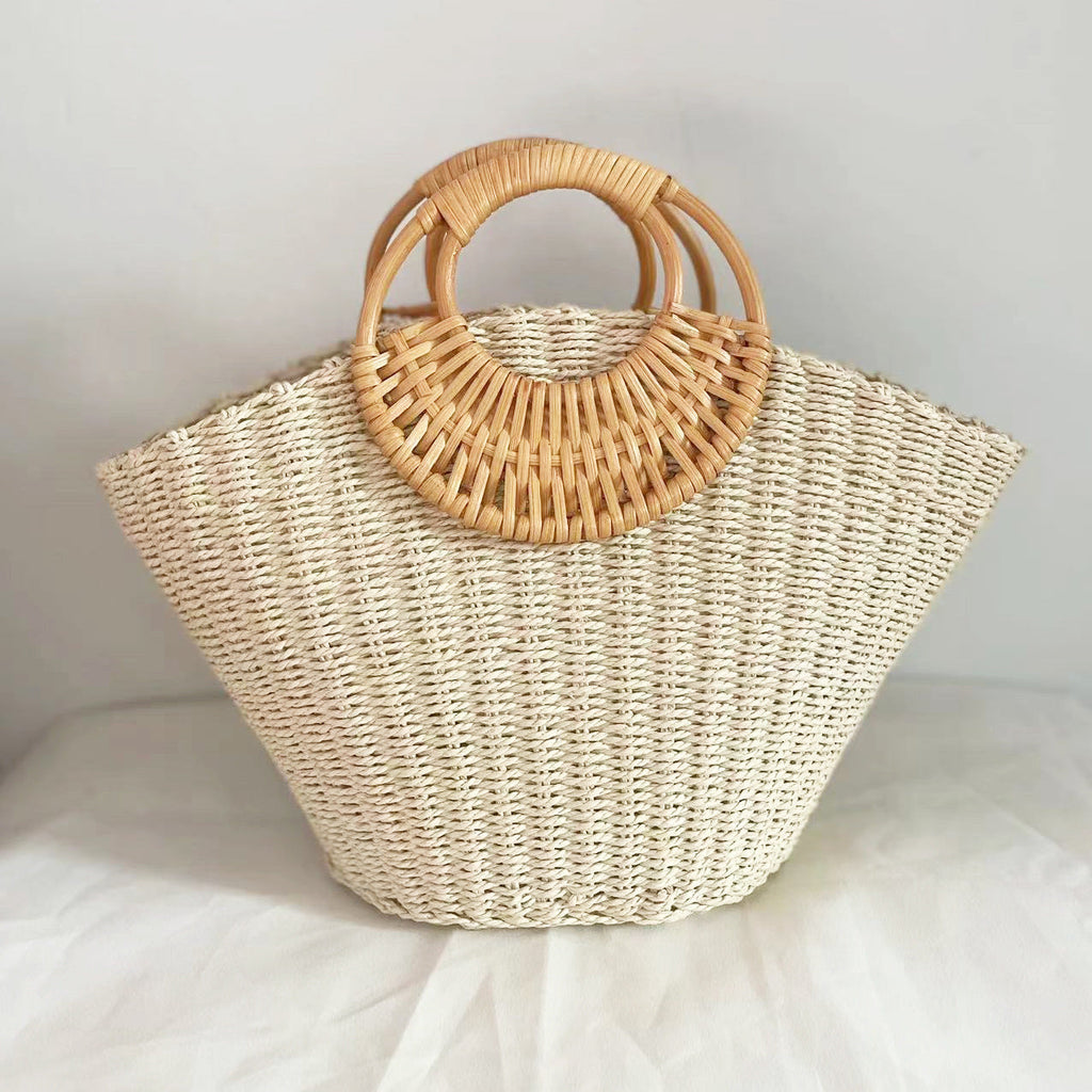 Lila woven straw tote bag in natural tones with wooden handles, perfect for carrying beach essentials. 0