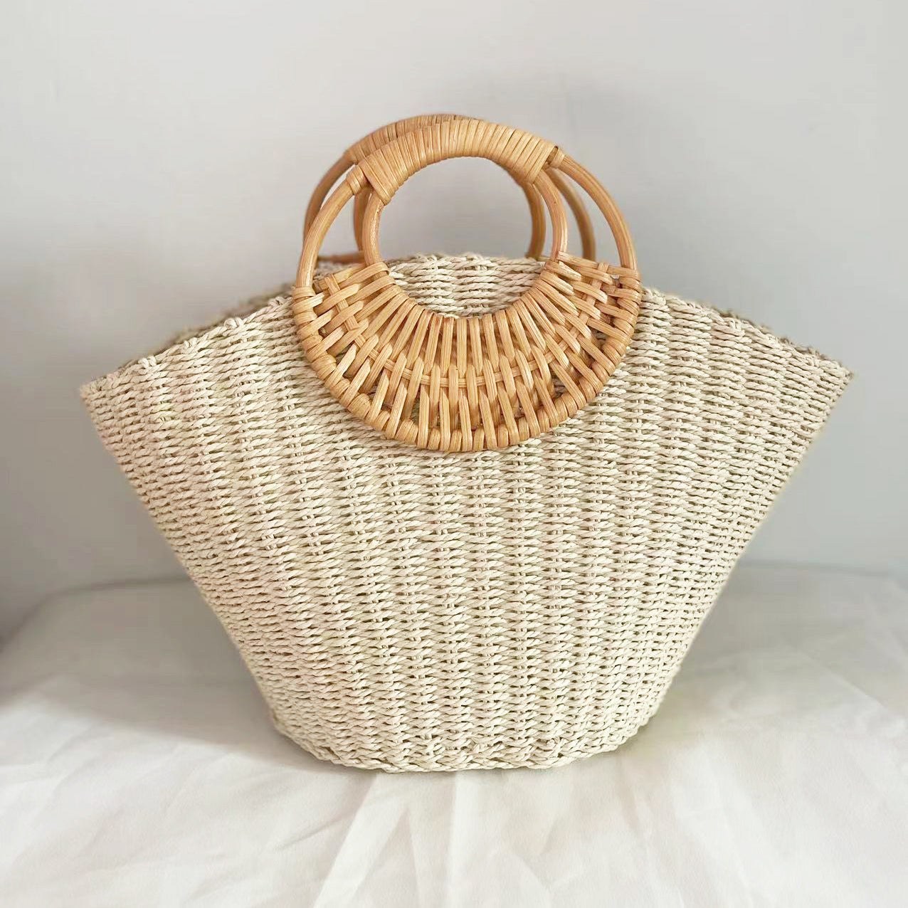 Lila woven straw tote bag in natural tones with wooden handles, perfect for carrying beach essentials. 0
