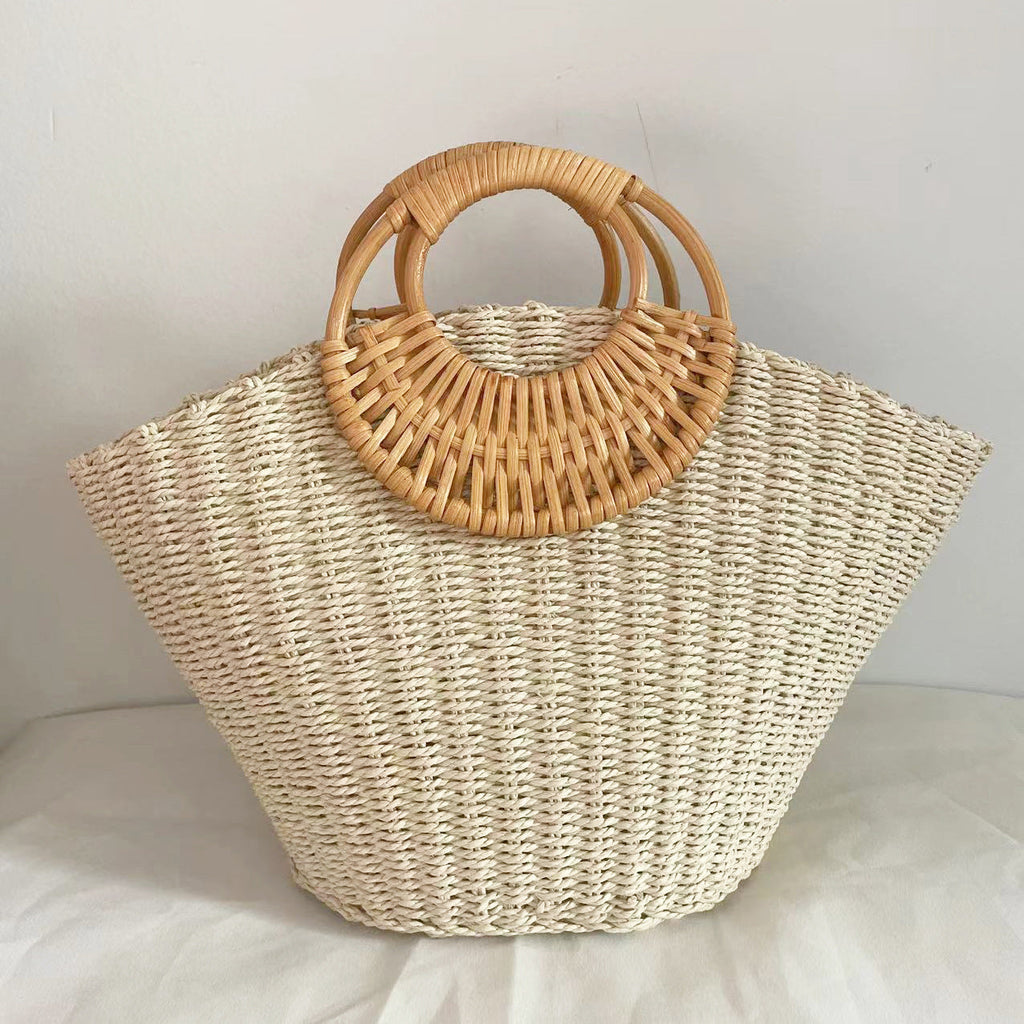 Lila woven straw tote bag in natural tones with wooden handles, perfect for carrying beach essentials. 2