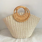Lila woven straw tote bag in natural tones with wooden handles, perfect for carrying beach essentials. 2
