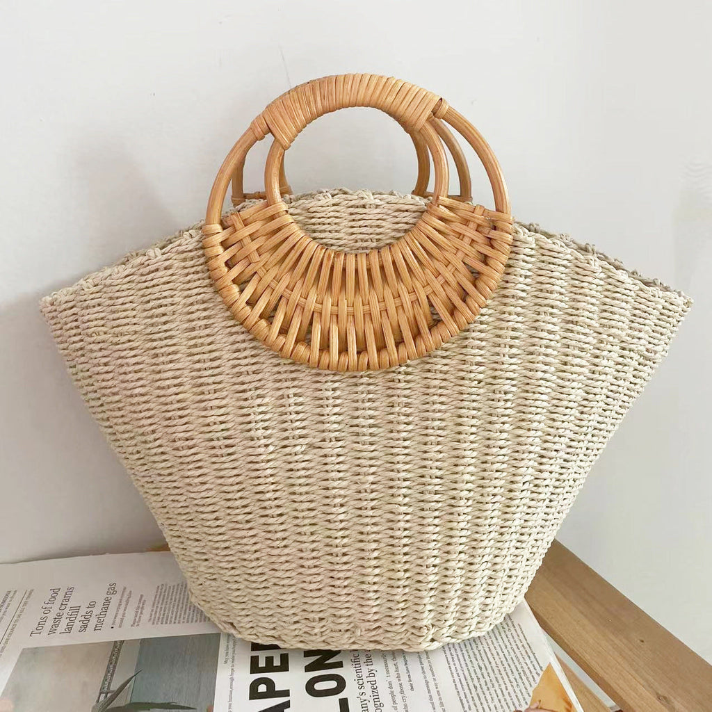 Lila woven straw tote bag in natural tones with wooden handles, perfect for carrying beach essentials. 3