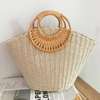 Lila woven straw tote bag in natural tones with wooden handles, perfect for carrying beach essentials. 3