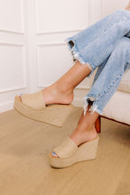 Tan jute wedge sandals with a wide woven strap and 4-inch heels, featuring a casual, bohemian style. 1
