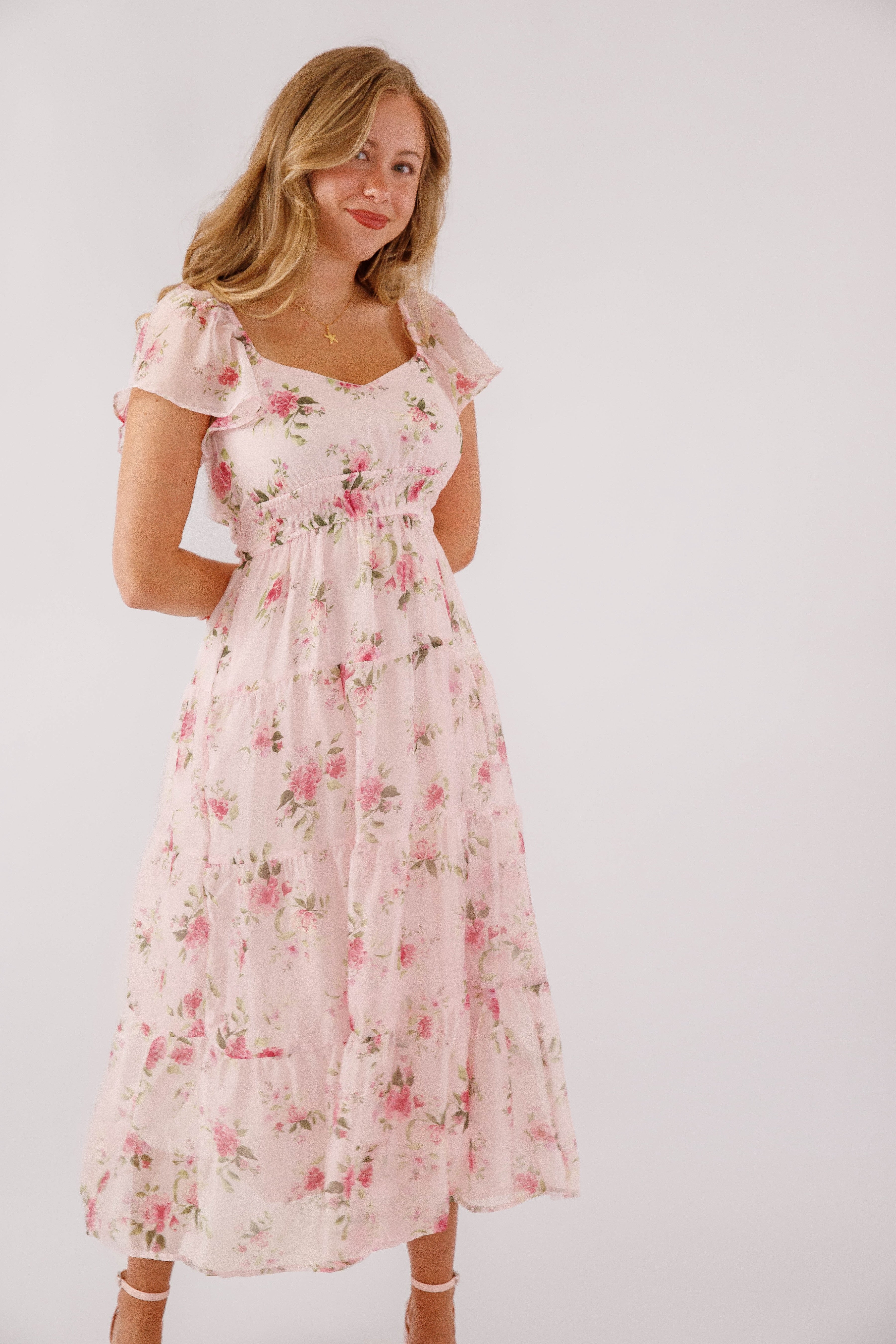 Blush pink midi dress with a floral pattern and flutter sleeves, perfect for wedding guests. 0