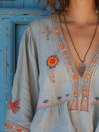 Flowy white bohemian blouse with delicate lace details and vibrant floral patterns. 2