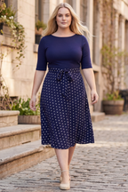 Navy blue midi dress with white polka dots, flared skirt, and a waist tie detail. 1