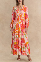 Flowy pink floral maxi dress with a V-neckline and long sleeves, featuring a smocked bodice for a relaxed fit. 0
