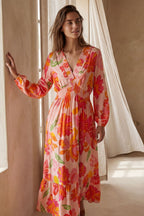Flowy pink floral maxi dress with a V-neckline and long sleeves, featuring a smocked bodice for a relaxed fit. 1