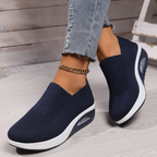 Navy knitted orthopedic slip-on sneakers for women with a cushioned wedge sole.