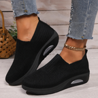 Black knitted slip-on sneakers for women with a cushioned wedge sole.