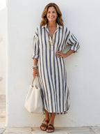 A striped midi shirt dress in navy blue with buttons down the front and long sleeves. 0