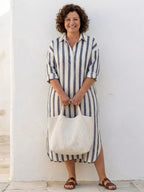 A striped midi shirt dress in navy blue with buttons down the front and long sleeves. 2