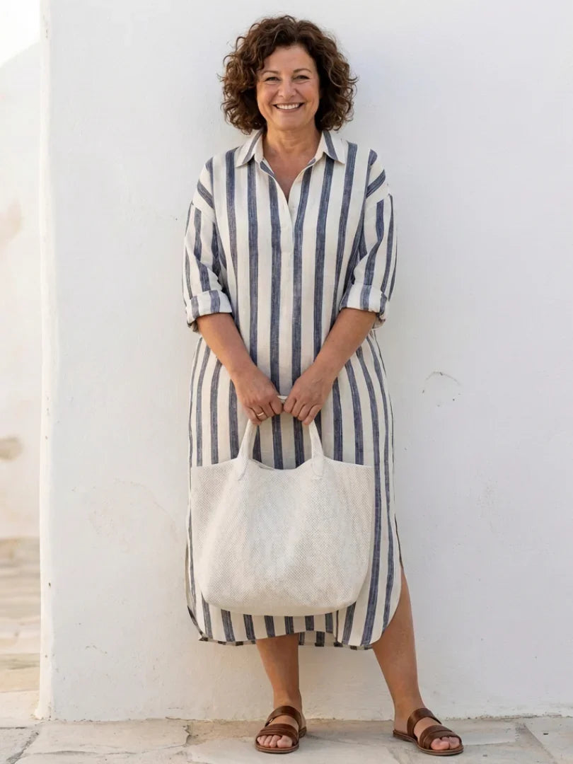 A striped midi shirt dress in navy blue with buttons down the front and long sleeves. 2
