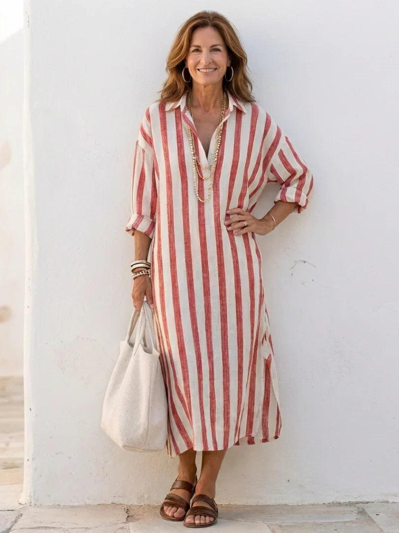 A striped midi shirt dress in navy blue with buttons down the front and long sleeves. 3